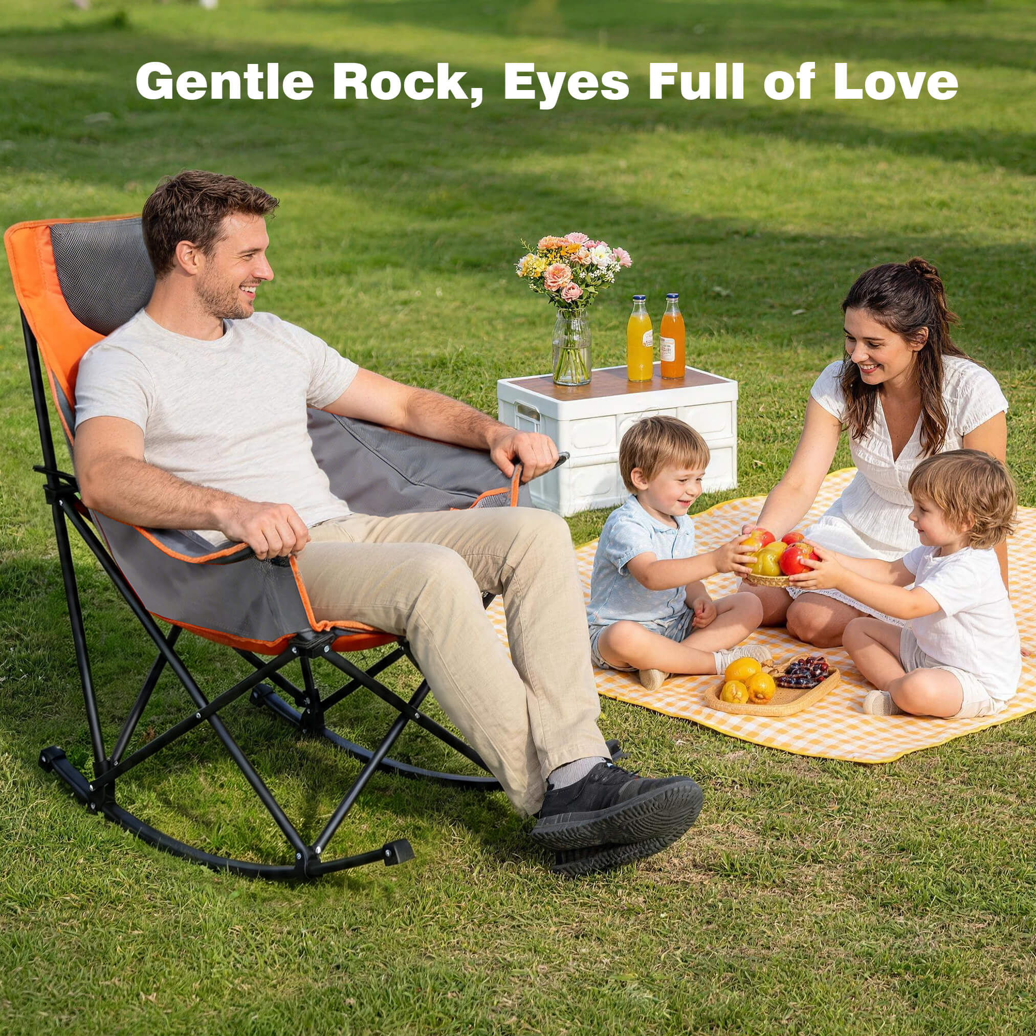 Family enjoying a picnic on a grassy field with a person in a rocking chair.