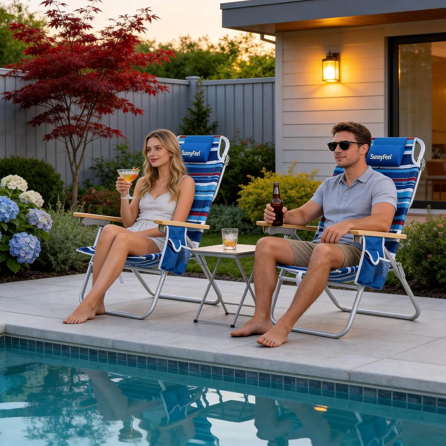 Two people sitting in blue lounge chairs by a poolside, enjoying drinks.