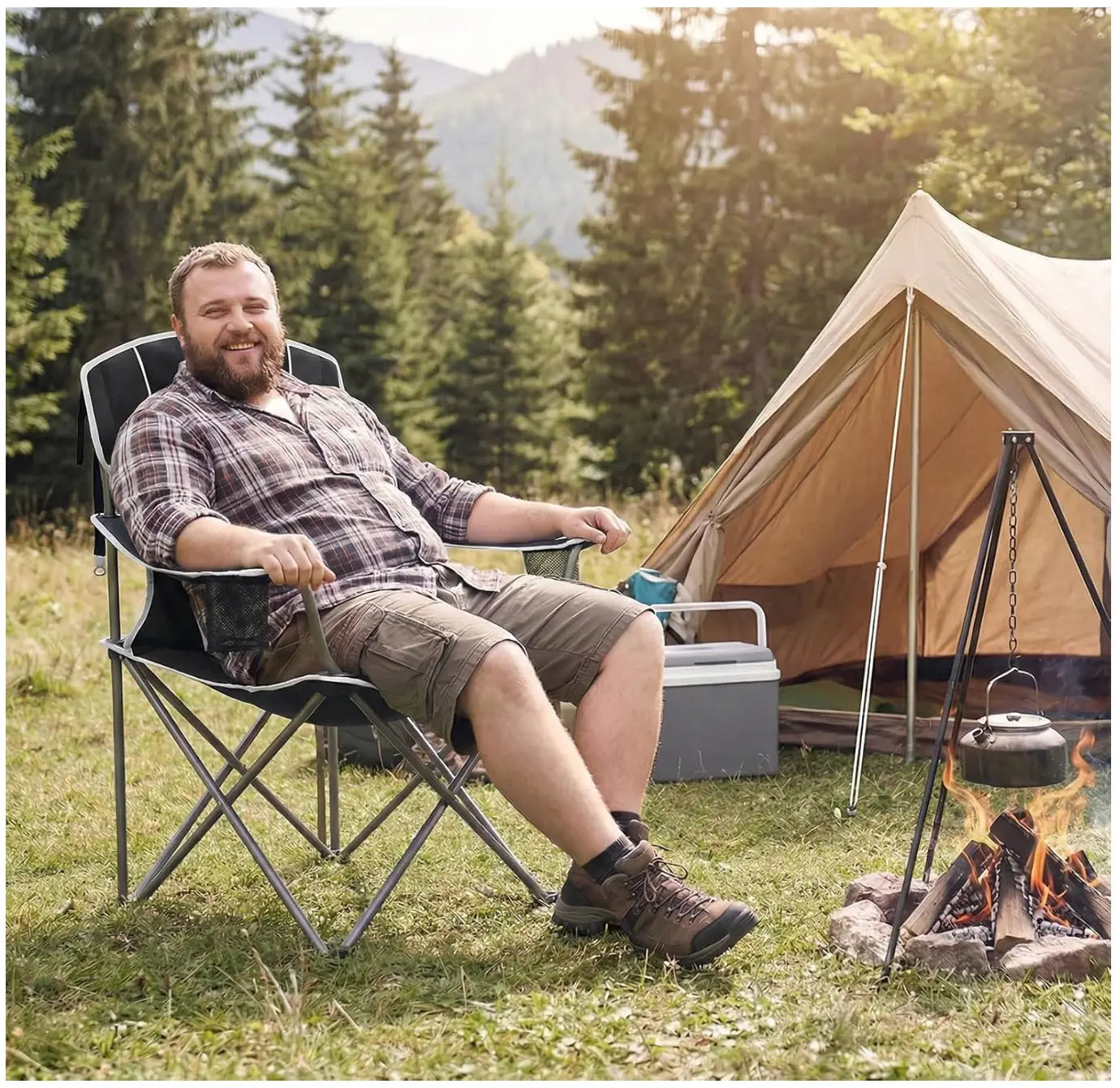 Man sitting in a camping chair by a tent and campfire in a forest setting