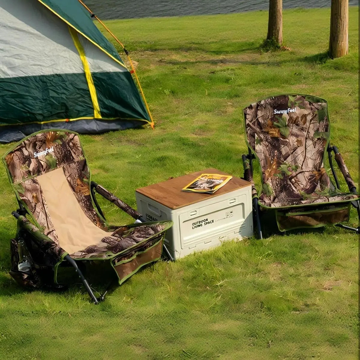 Camping scene with camouflage chairs, a table, and a tent by a body of water.