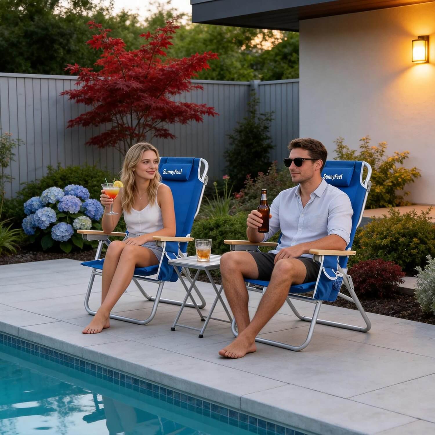 Two people sitting in blue folding chairs by a pool, enjoying drinks.