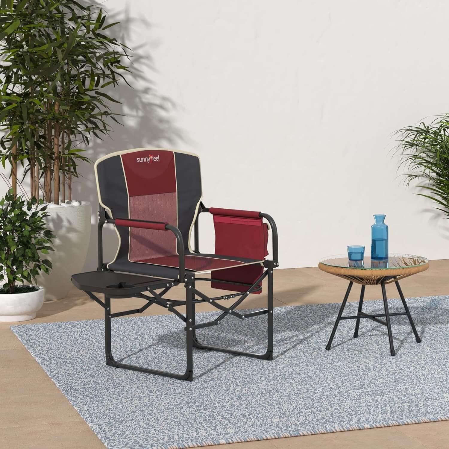Outdoor chair with red and gray design on a patio with a small table and plants.