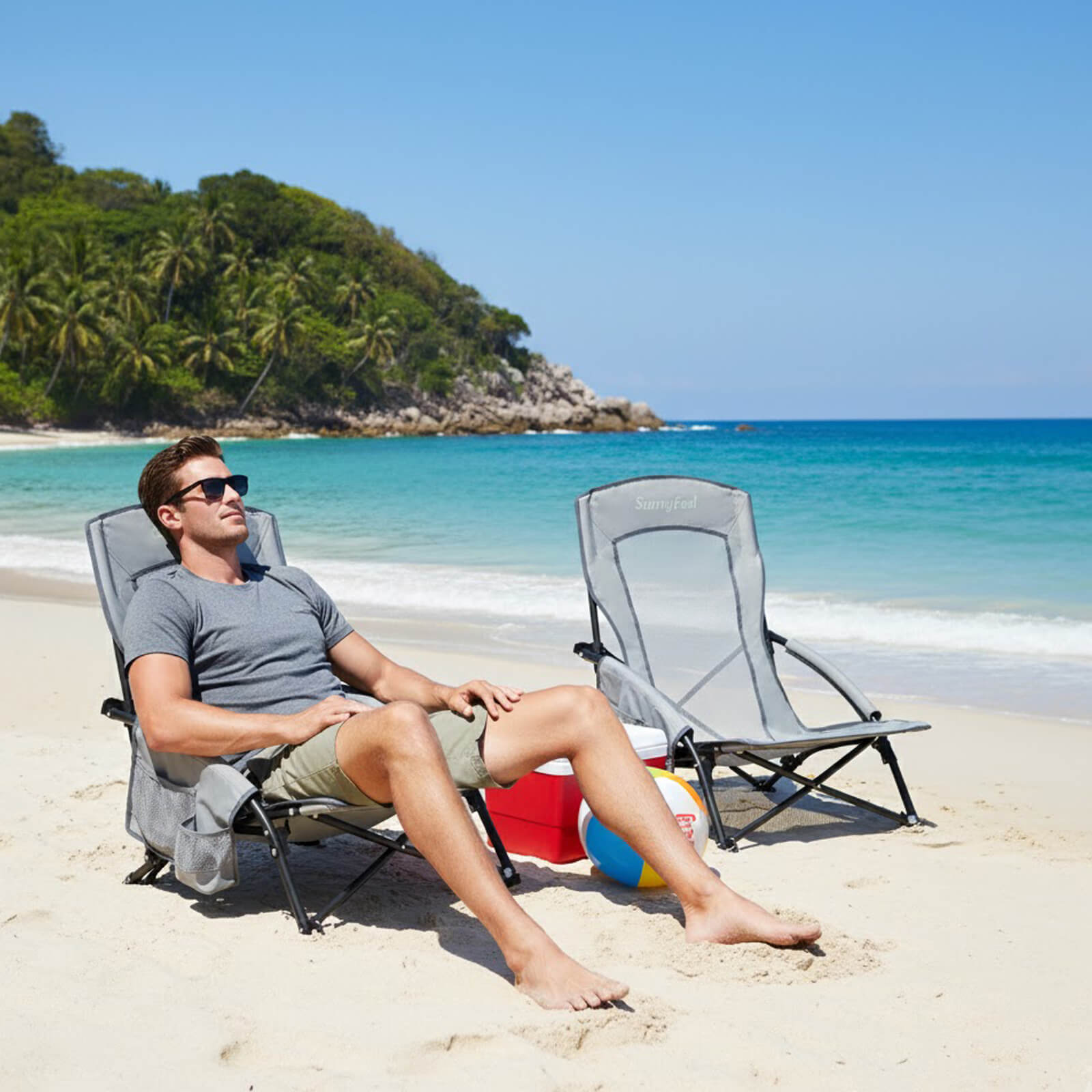 Man relaxing on a beach chair by the ocean with another chair nearby.