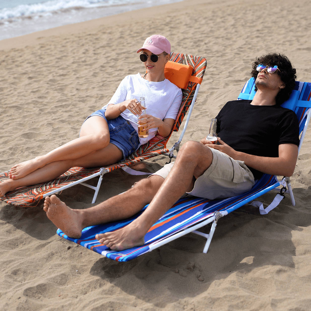 Two people relaxing on beach chairs by the ocean.