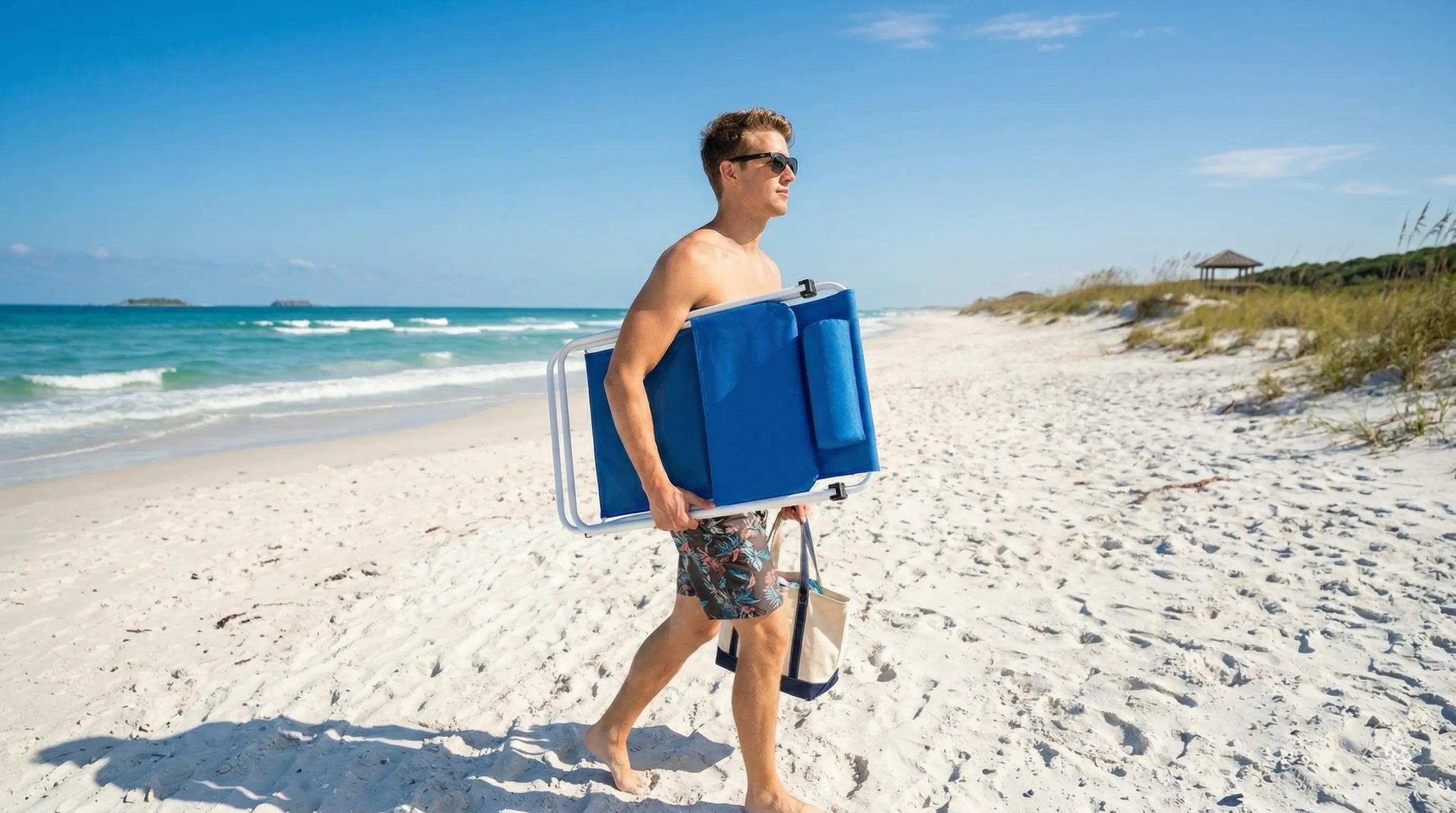 Man walking on a beach carrying a blue cooler.