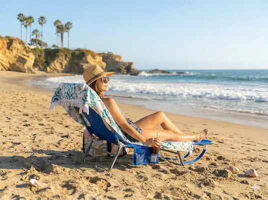 Woman relaxing on a beach chair by the ocean with palm trees in the background