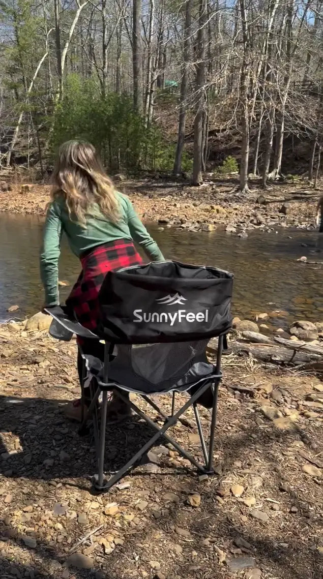 Person sitting on a SunnyFeel chair by a river with a bag on their lap