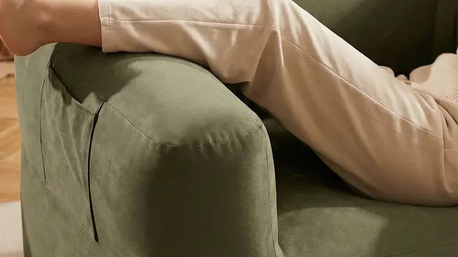 Person sitting on a green couch wearing beige pants.