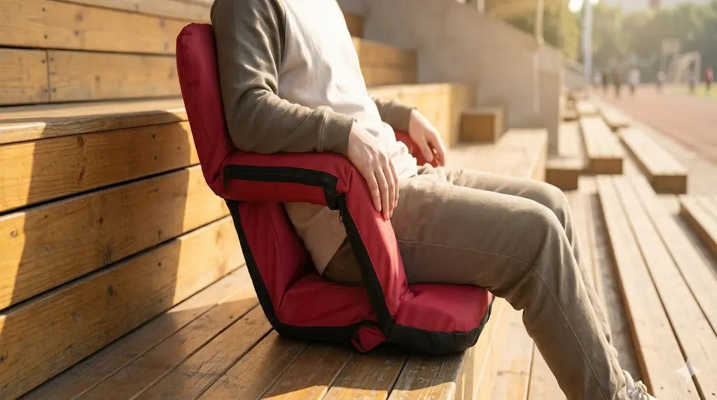 Person sitting on a red and black portable chair on a wooden floor.