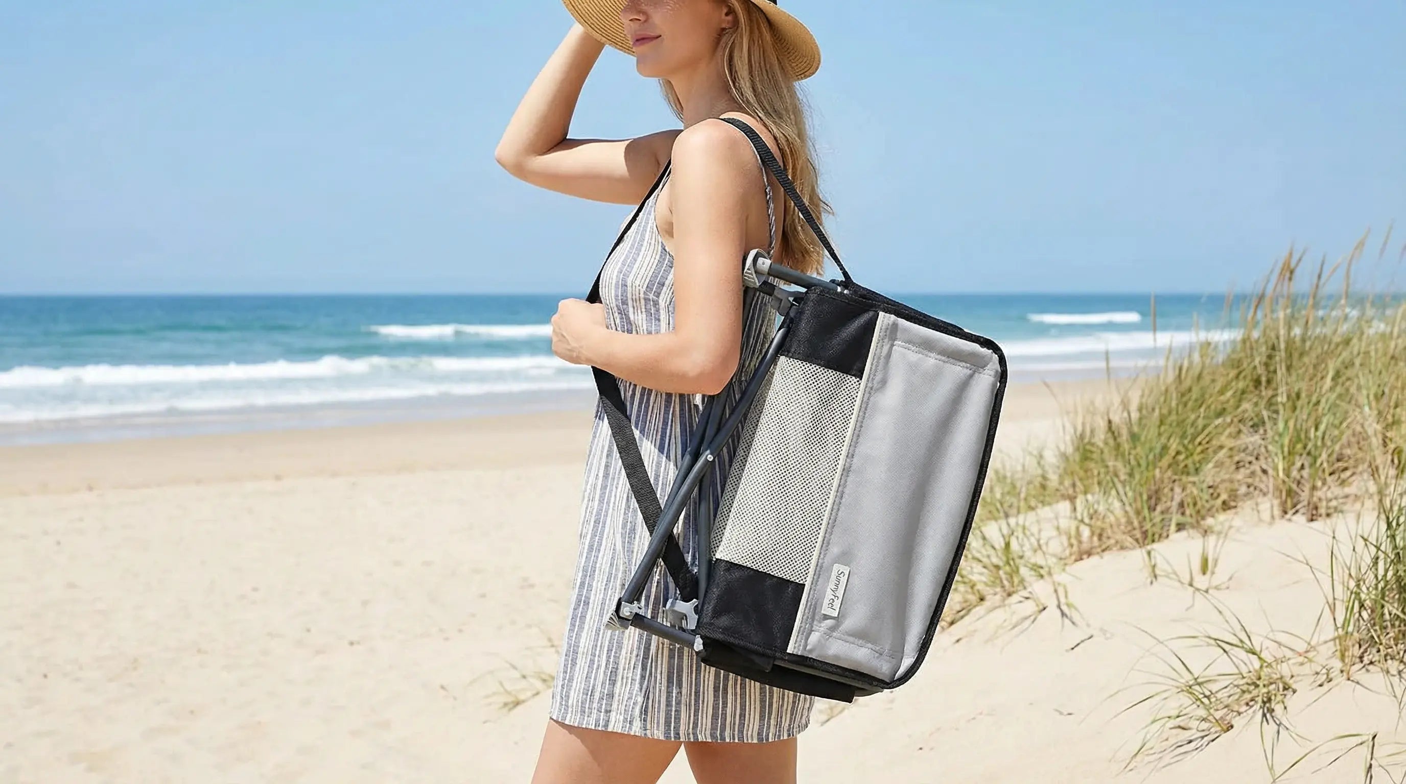 Woman on a beach holding a black and gray tote bag