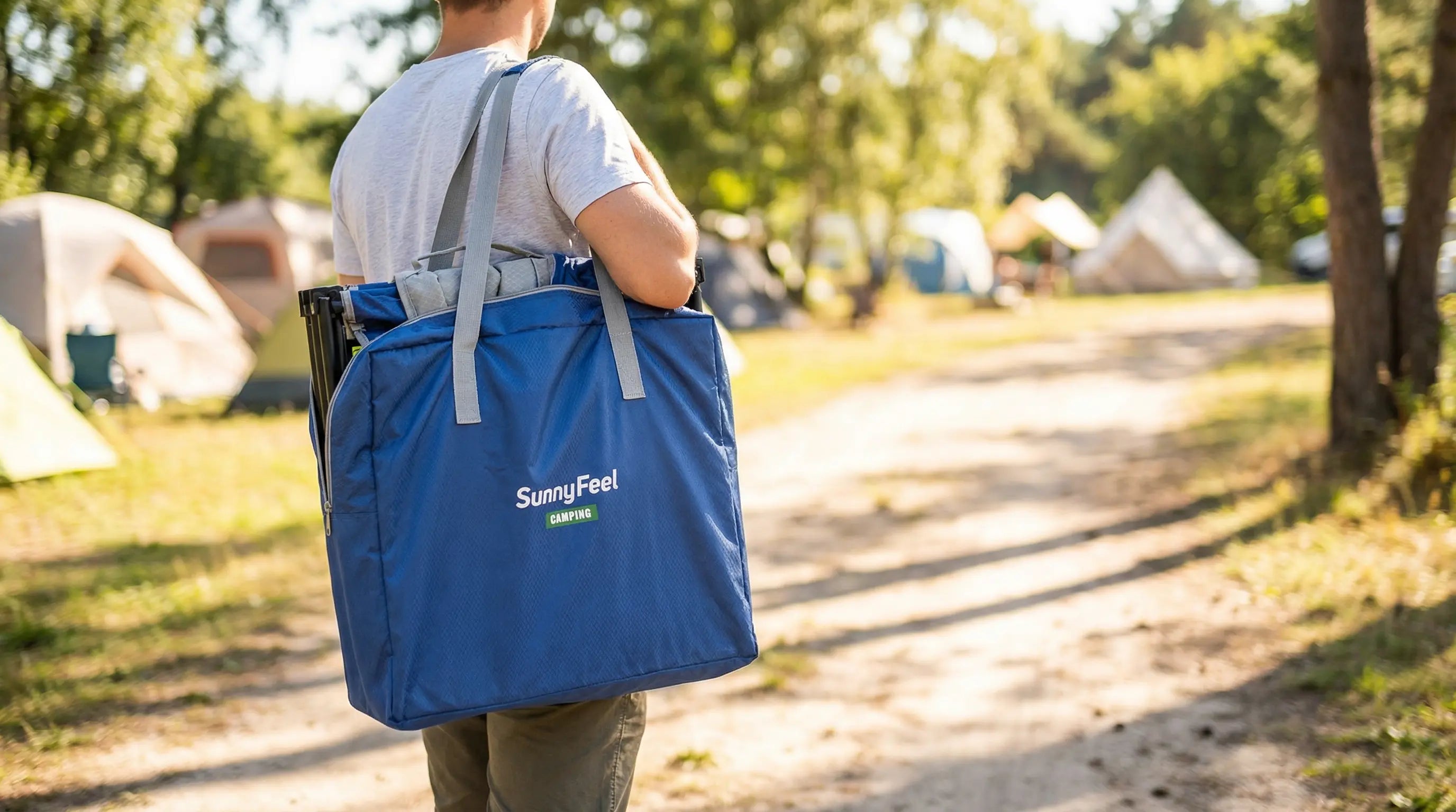 Person carrying a blue bag with 'Sunfei' branding in a camping area.