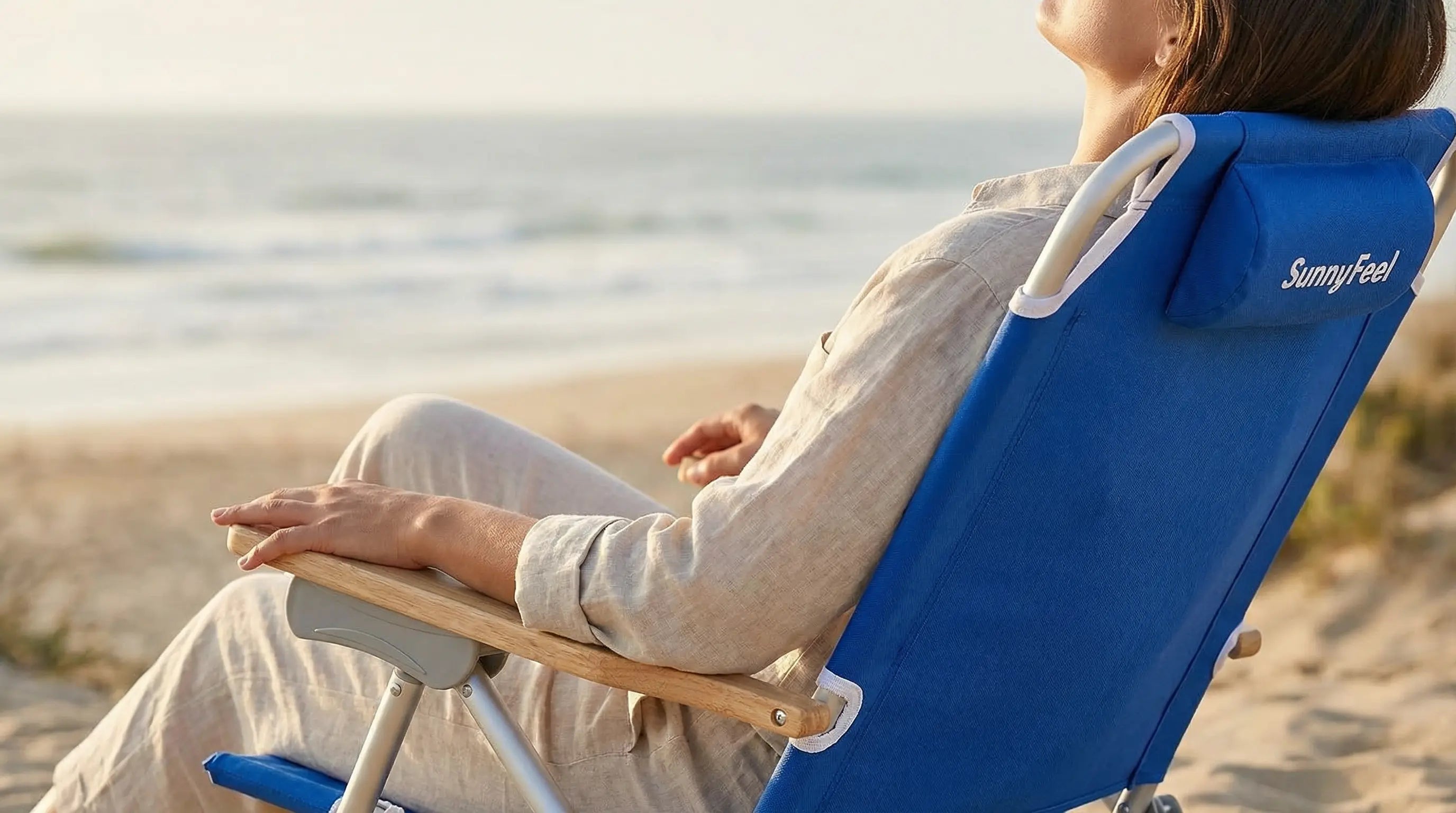 Person sitting on a blue SunnyFeel beach chair by the ocean.