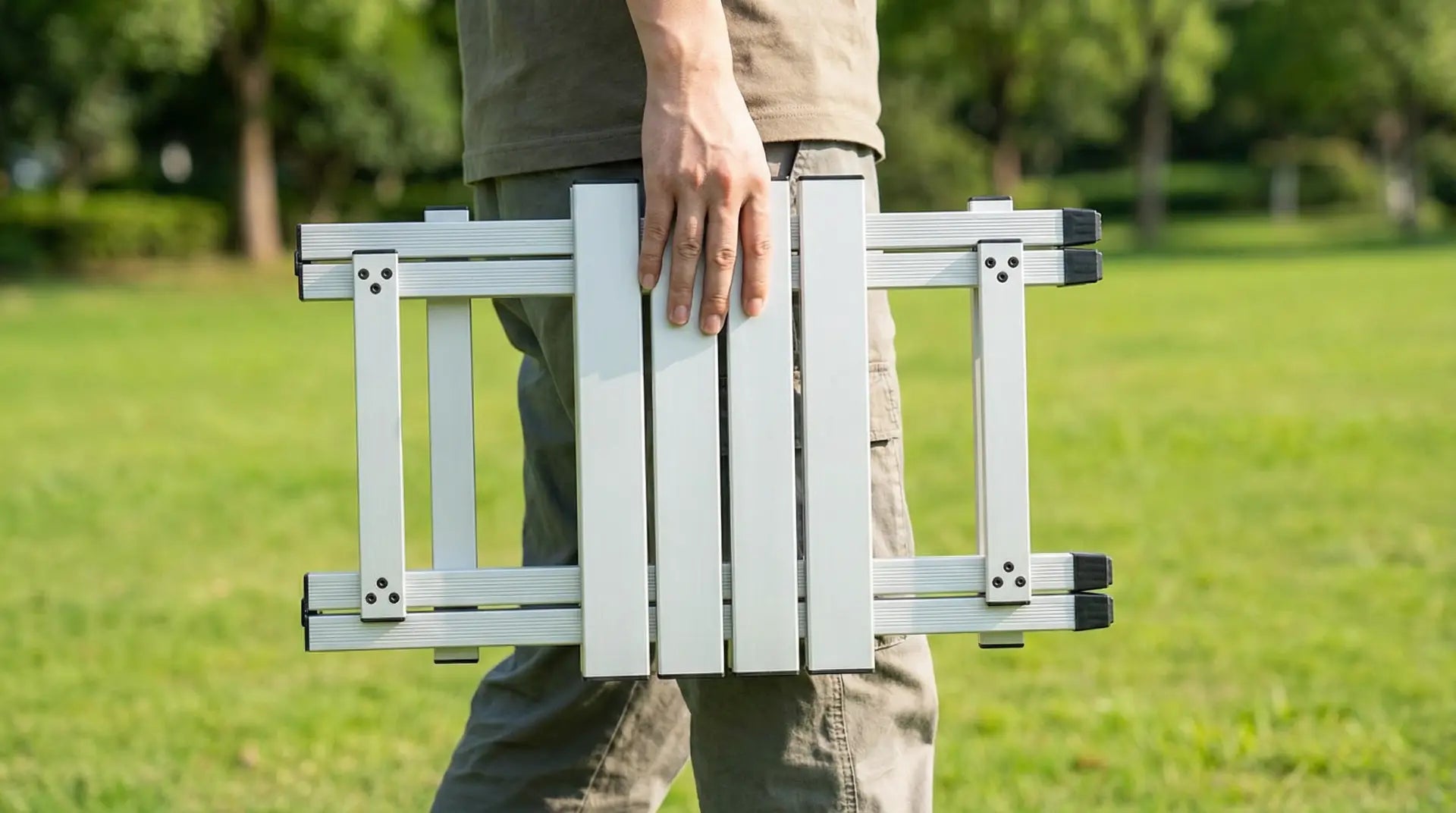 Person holding a portable folding stool in a park