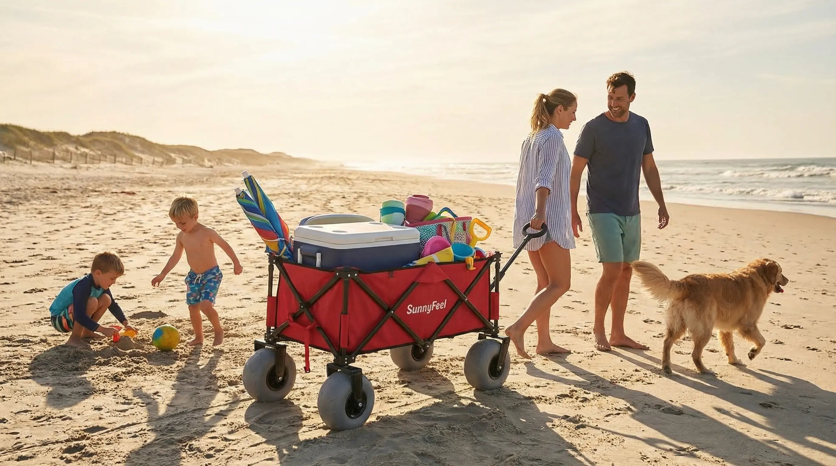 Family with children and a dog on a beach with a red wagon full of toys.