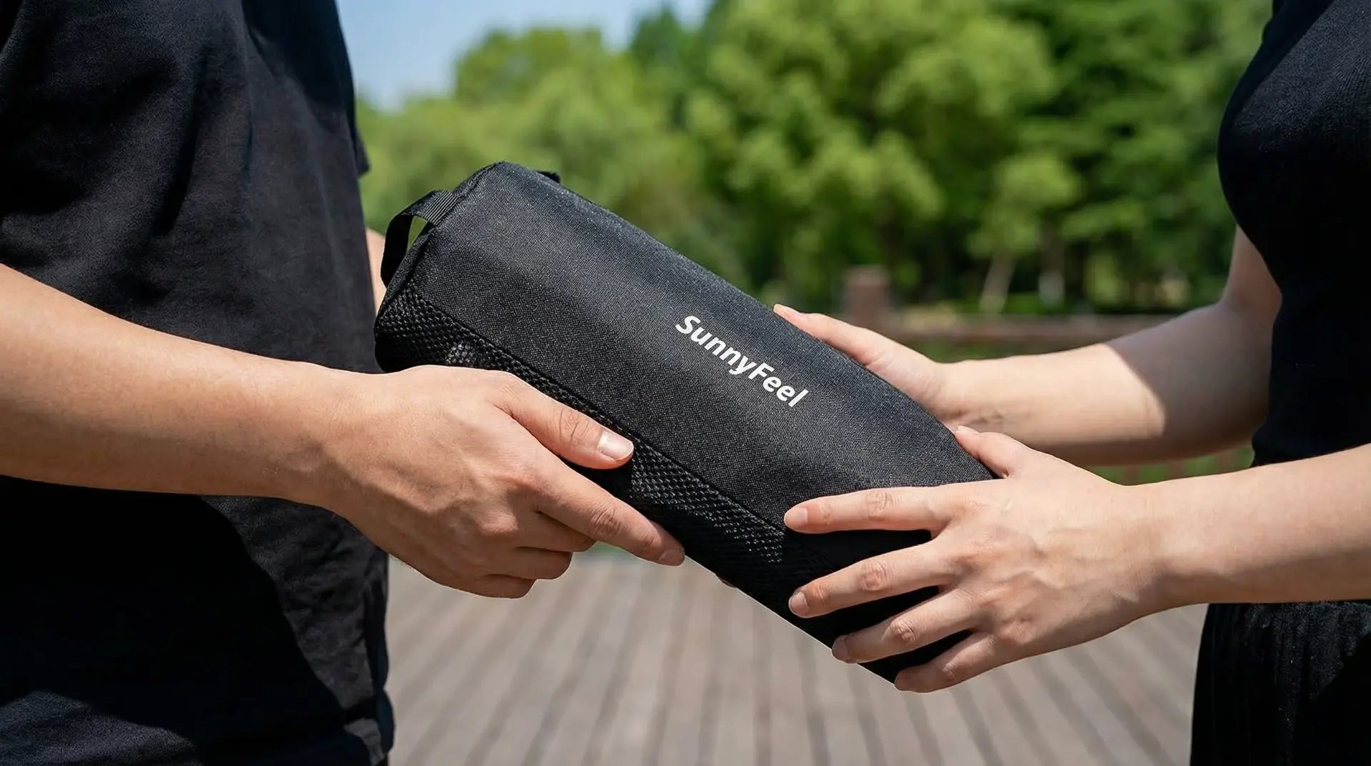 Two people holding a black SunnyFeel product outdoors with greenery in the background